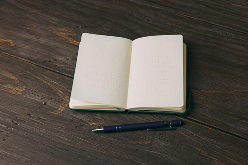 ノートとペンが並ぶ机の上の写真